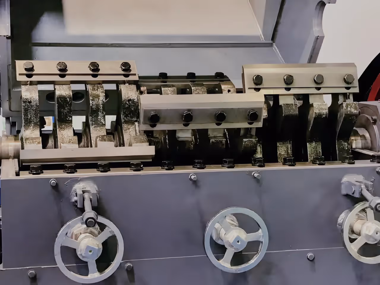 The cutting chamber of a plastic crusher, showing the staggered blade rotor and the external knife gap adjustment hand wheels.