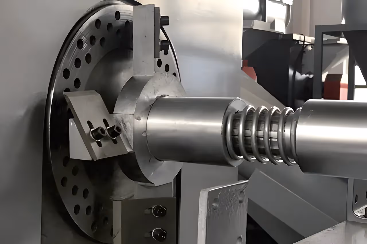 A close-up of a die-face pelletizer head on a plastic squeezer, showing the rotating cutting blades that granulate the extruded plastic.